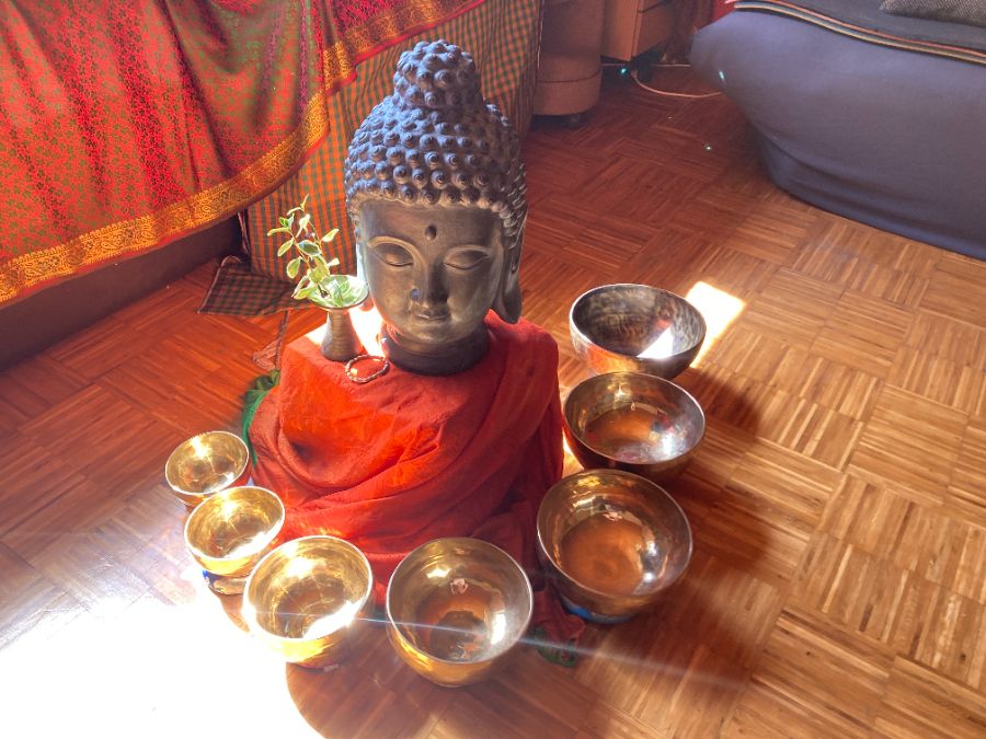 Klangschalen um eine Buddha-Figur im warmen Licht